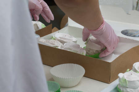 A woman collects homemade marshmallows in craft boxes. Marshmallow in the form of roses. Close-up...