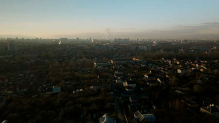 The suburb is backlit by the setting sun. Houses, a park area and a city highway are visible. Aerial photography.の写真素材