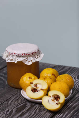Quince fruits on a plate. Quince jam. The yellow fruit is cut, the seeds are visible. Plate on black pine boards. Close-up shot.の写真素材