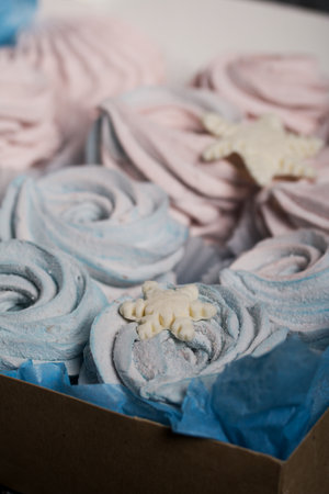 Marshmallow blue and pink. Lies in craft packaging. Decorated with mastic snowflakes. On black pine boards.の写真素材
