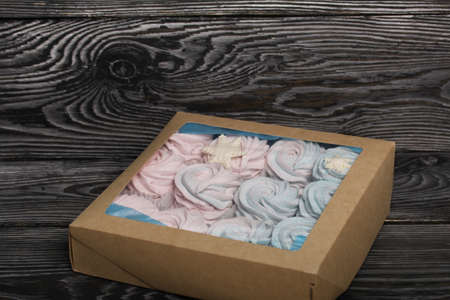 Marshmallow blue and pink. Lies in craft packaging. Decorated with mastic snowflakes. On black pine boards.の写真素材