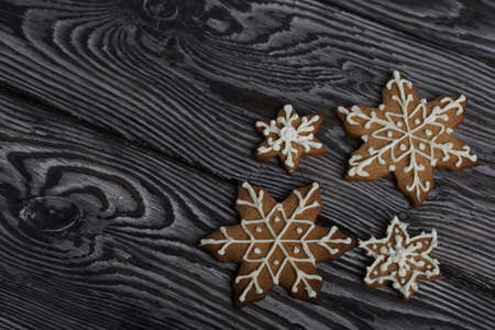 Gingerbread cookies in the shape of a snowflake. Decorated with sugar glaze. Gingerbread cookies in the shape of a snowflake. Lie on black boards. Close-up shot.の写真素材