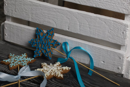 Gingerbread cookies in the shape of a snowflake. Decorated with sugar glaze. Gingerbread cookies on a stick in the shape of a snowflake. Lie on black boards. Close-up shot.の写真素材