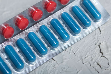 Blisters with red and blue tablets. On a light background. Close-up.