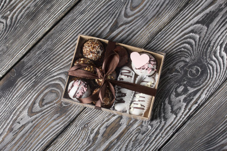 Candies in chocolate glaze. in a gift box. Tied with a ribbon tied into a bow. On pine boards.の写真素材