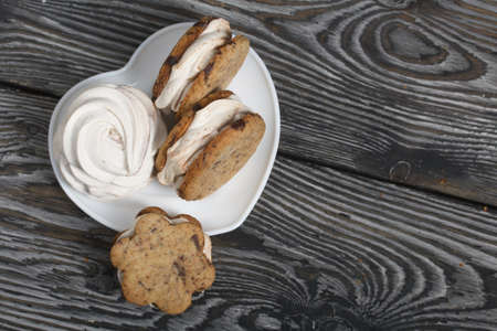 Homemade marshmallows and zephyr sandwiches. They lie on a white plate. Against the background of pine boards. close-up.の写真素材