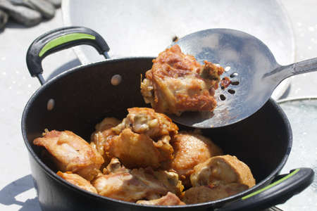 Chicken thighs are fried in a cast-iron cauldron. Cooking outdoors. close-up.の写真素材