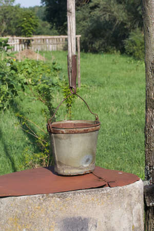 Old village well made of concrete circles. A bucket is hung over it.の写真素材