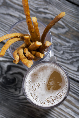 Thin sausages for beer in a beer glass. Next to it is a glass of wheat beer. background from pine...