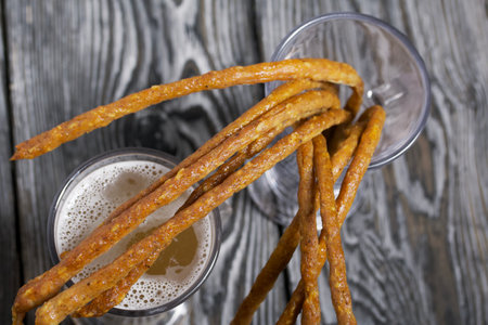 Thin sausages for beer in a beer glass. Next to it is a glass of wheat beer. background from pine boards. close-up.の写真素材