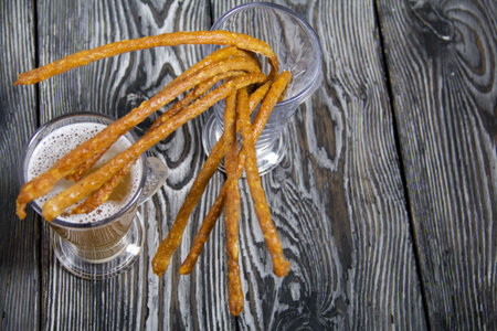Thin sausages for beer in a beer glass. Next to it is a glass of wheat beer. background from pine...