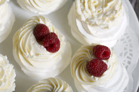 Cake Anna Pavlova, meringue and cream. Garnished with raspberries. Lying on a platter, close up.の写真素材