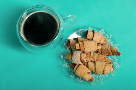 Rolls with cinnamon. Croissants with cinnamon. They lie on a saucer. There is a cup of coffee next to it. light green background. Shot close-up.の写真素材