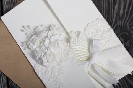 Homemade greeting card in white. With decorative elements. Ribbons, flowers and leaves are attached...