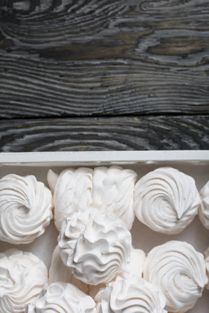 homemade zephyr. White tray with marshmallows. Stands on black pine boards.の写真素材