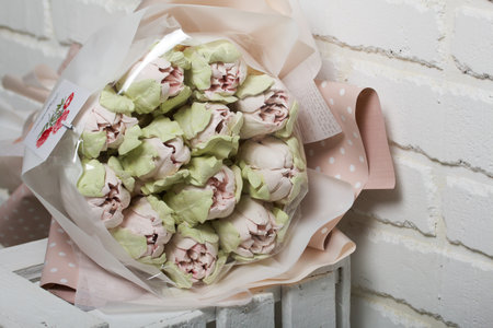 Marshmallow bouquet. Zephyr tulips. Natural homemade marshmallow. Packed in paper in the form of a bouquet. On a wooden box. close-up.の写真素材