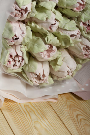 Marshmallow bouquet. Zephyr tulips. Natural homemade marshmallow. Packed in paper in the form of a bouquet. On pine boards. close-up.の写真素材