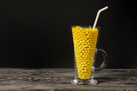 The glass goblet is filled with vitamins in the form of dragees. On black pine boards. On a black background.の写真素材