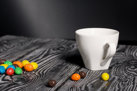 A cup of black coffee in a white cup. Chocolate candy in glaze. On pine boards.の写真素材