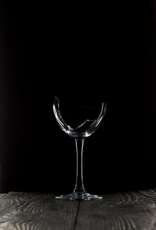 Broken glass goblet. Stands on black boards. Shot on a black background.の写真素材