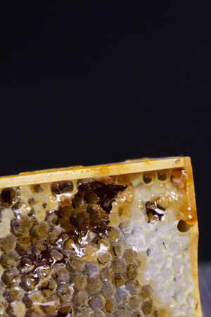 Honey in honeycombs in a wooden frame. On black pine boards. On a black background. close-up.