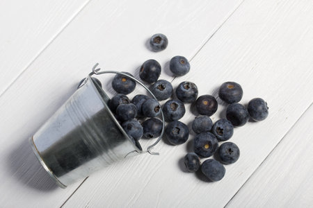 Overturned decorative bucket. Scattered large blueberries. International day without diets. On a white background. close-up.の写真素材