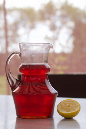 Red compote in a glass decanter. Summer drink from berries and fruits. Next to the table are the...