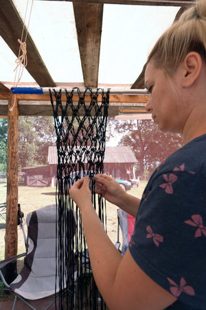 A woman weaves a string bag from a polymer cord. Homemade shopping grid.