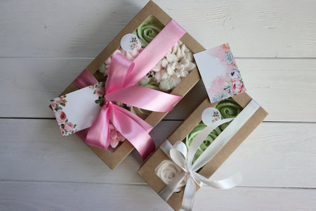 Two boxes with marshmallows. Zephyr flowers. Homemade marshmallows in a paper gift box. Gift box with a bow and ribbons on a white wooden backgroundの写真素材