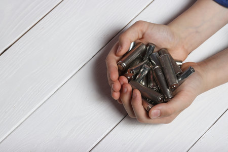 Detailed image of a teenager's hands holding spent finger batteries, promoting waste recycling and...