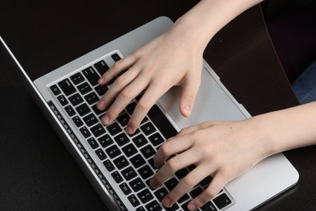 Teenager's hands in close-up position on a laptop keyboard, illustrating a fluency in technology and...