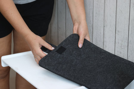 A woman is demonstrating a laptop sleeve case. The case is made of felt.の写真素材