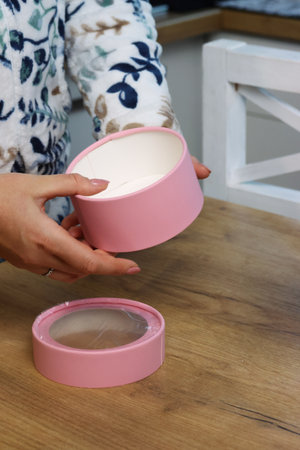 A woman reviews a gift box with a window. A small pink box. Gift wrapping.