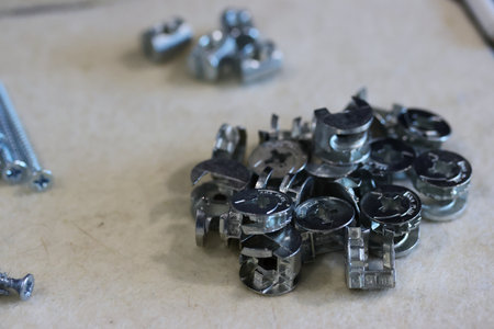 Hardware for assembling an ottoman. Laid out for convenience. Close-up view.