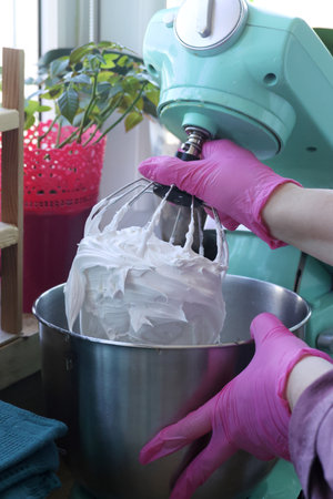 A woman checks the prepared marshmallow mixture. Marshmallow mixture in the mixer bowl and on the...