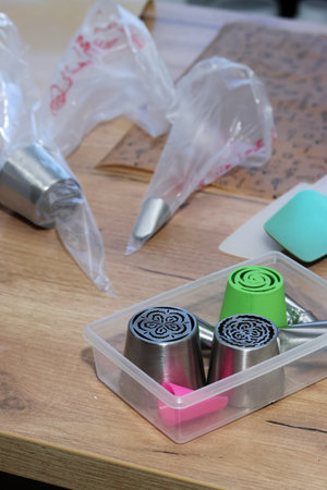 Metal and plastic pastry tips for making marshmallow flowers. Nearby are pastry bags with tips.