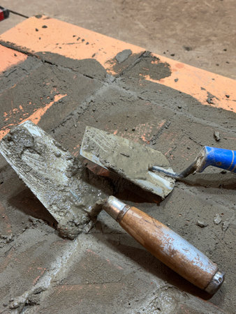 Two trowels on the brickwork of a heating stove base. Close-up.の写真素材