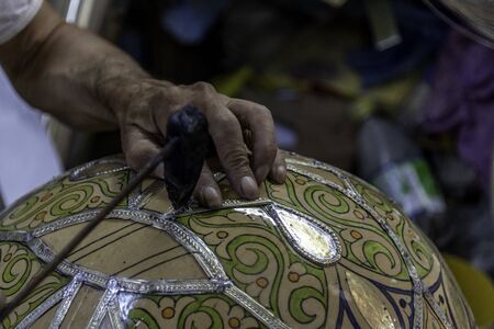 Close-up hands applying metal outline to ceramic bowlの写真素材