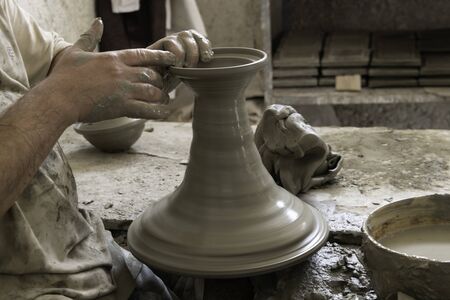 Close-up hands using pottery wheel making large ceramic vaseの写真素材
