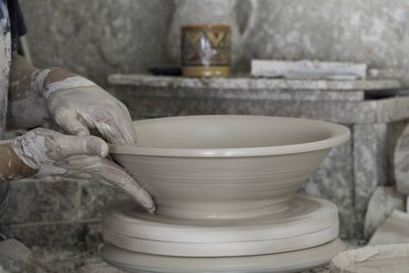 Close-up hands using pottery wheel making large ceramic bowl
