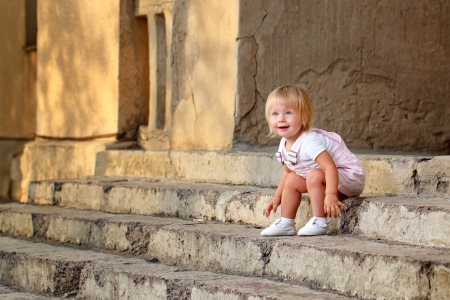 Blond girl with blue eyes sitting on the porch stepsの写真素材