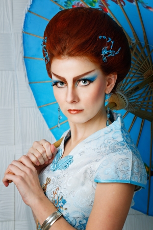 Attractive geisha in a smart dress with an umbrella, photographed in the studioの写真素材