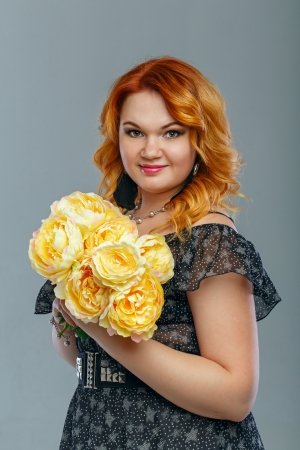 Attractive red-haired girl holding a bouquet of yellow flowersの写真素材