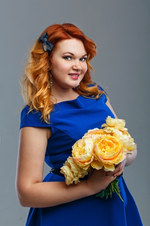 Attractive red-haired girl holding a bouquet of yellow flowersの写真素材