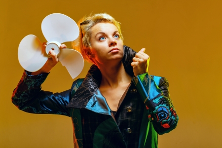 Girl in a jacket with a fan in hands, shot in the studioの写真素材