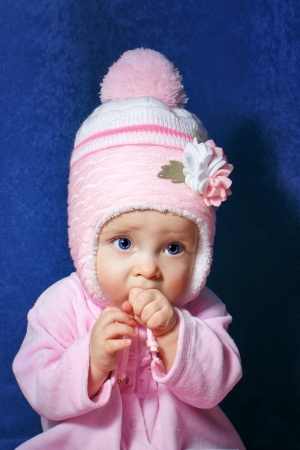 Cute little girl with blue eyes wearing pink hatの写真素材