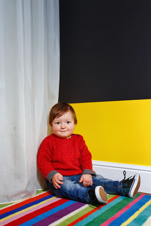Cute little boy sitting on the floor in the living roomの写真素材