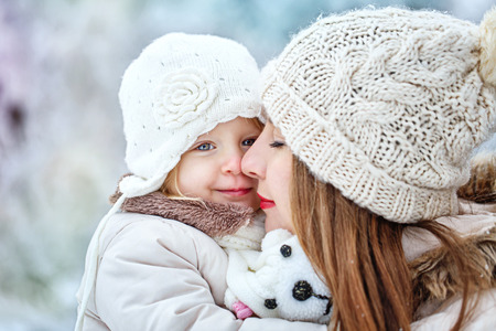 Young mother holding a daughter in a winter forest for a walkの写真素材