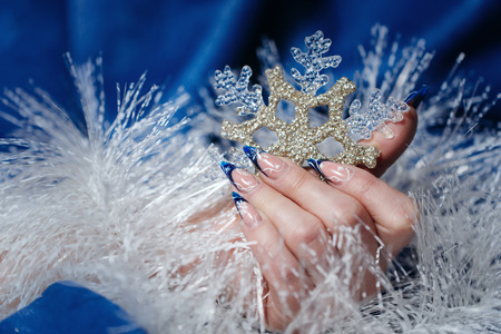 Female hand with beautiful manicure holding a snowflake shot closeupの写真素材