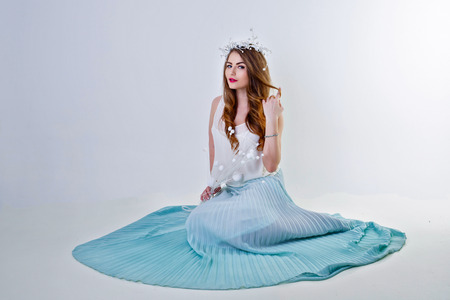 Young attractive girl in a light fairy dress sitting on the floorの写真素材